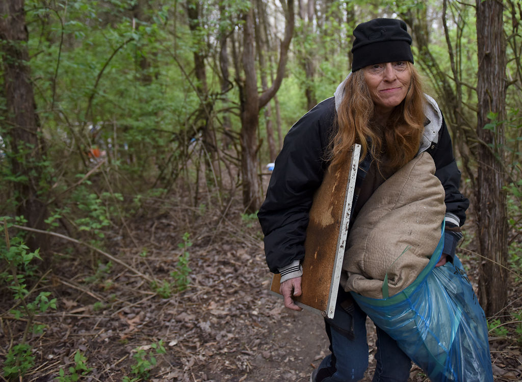 Volunteer Diana Welch carries some items out of the abandoned campsite